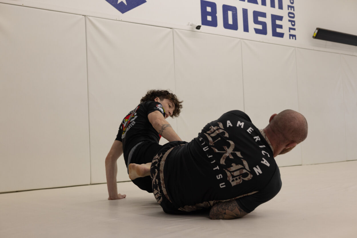 Two jiu-jitsu athletes rolling on the mat during a live training round