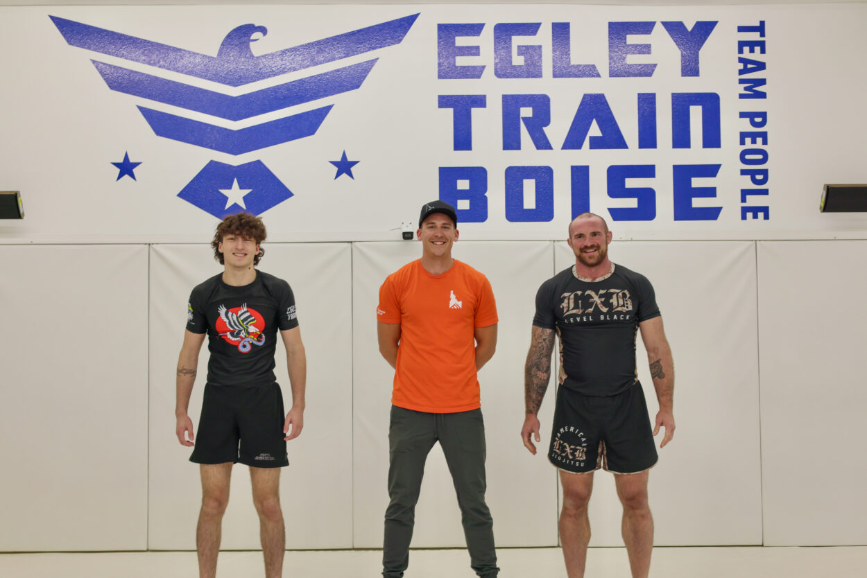 Three athletes standing on a jiu-jitsu mat at Egley Train Academy in Boise, Idaho, in front of gym logo