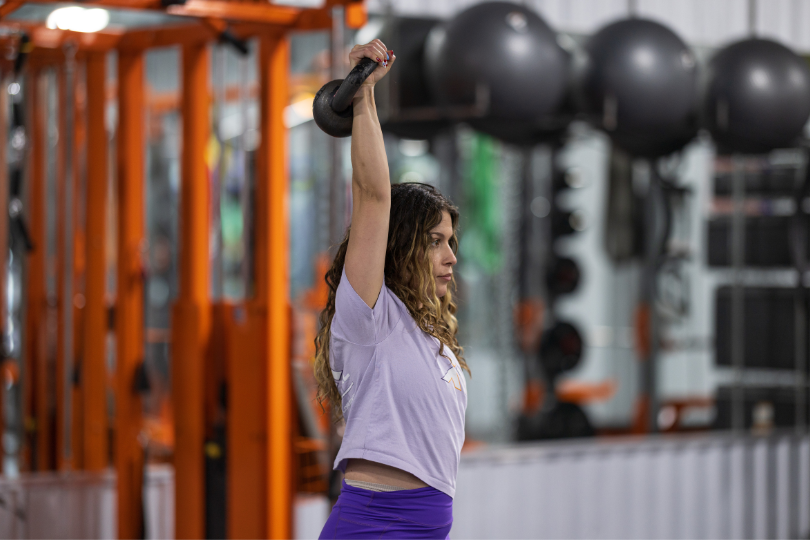 Coach Jacqueline performing a single-arm kettlebell overhead press at Functional Idaho.