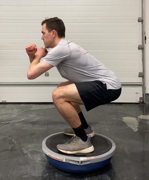 man doing a squat on a balance ball