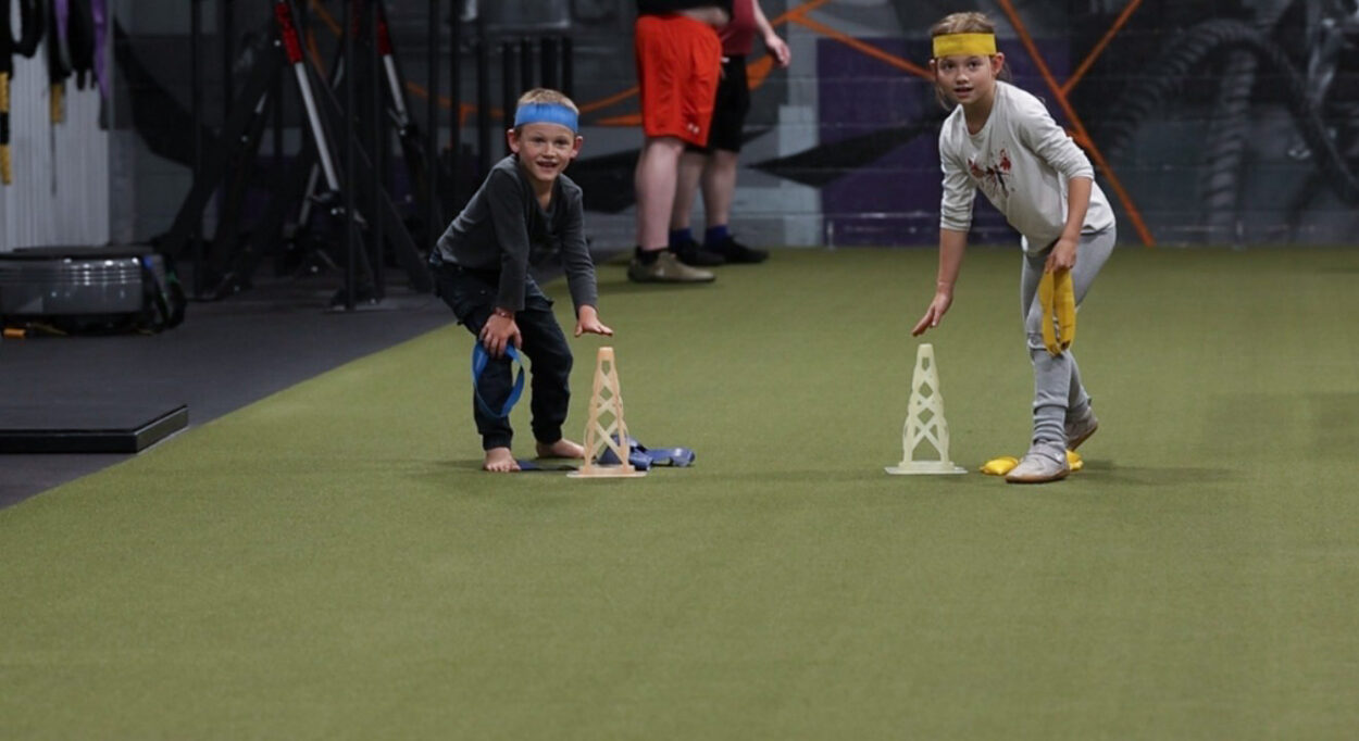 Two children participating in a youth strength and conditioning class at Functional Idaho, developing coordination, athletic skills, confidence, and teamwork through fun movement-based training.