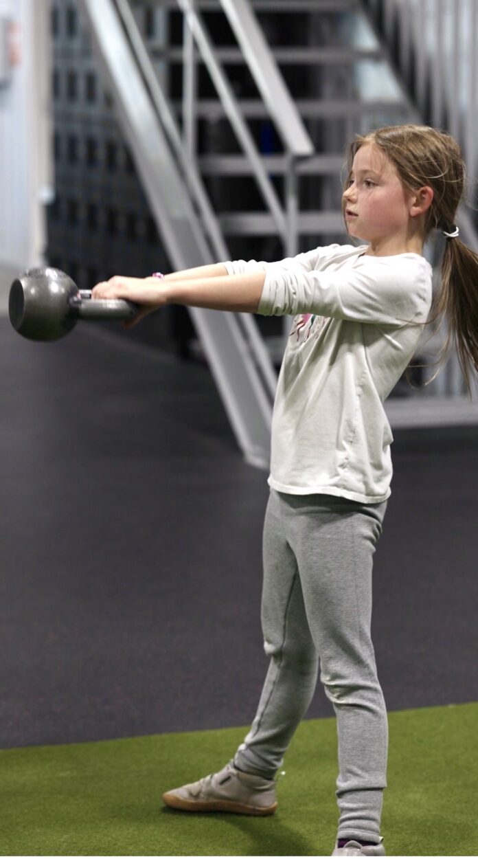 Young athlete practicing kettlebell training during a youth fitness class at Functional Idaho in Boise, Idaho.